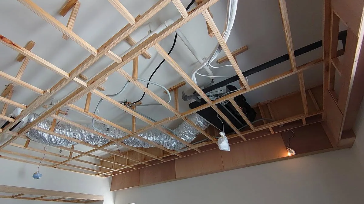 天花板木角材骨架已架設，冷氣軟管與電線配管外露，尚未封板