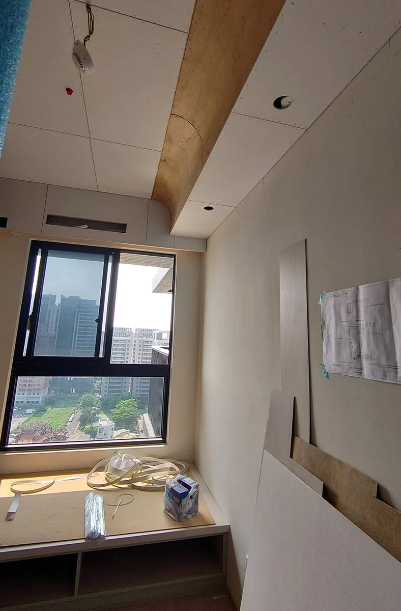 臥室天花板封板完成，窗邊臥榻櫃體施工中，牆面張貼施工圖面